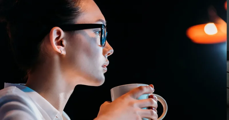 Frau sitzt abends allein mit einer Tasse und hängt Gedanken nach
